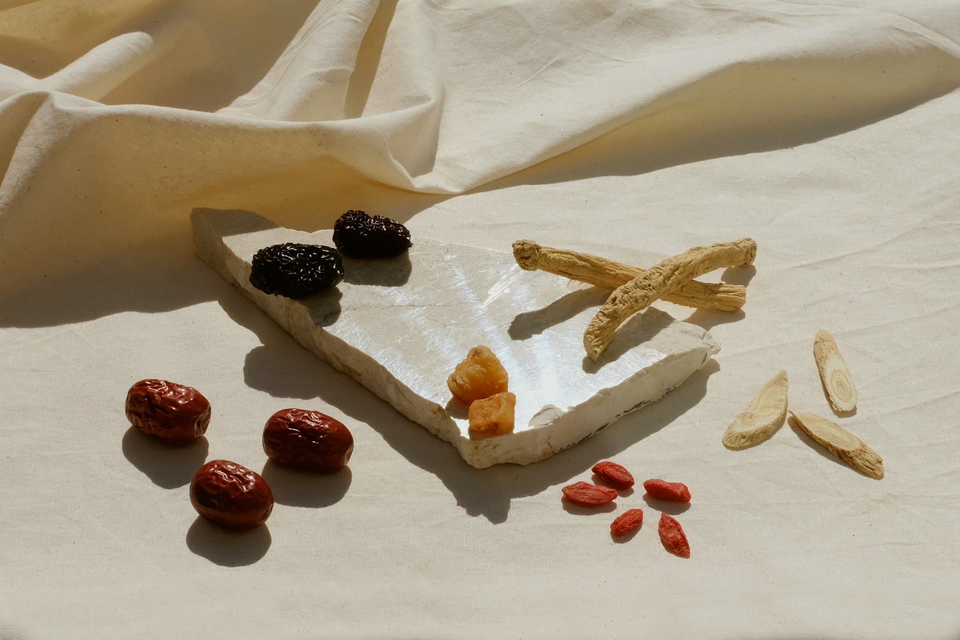 Chinese herbs red dates jujube, black dates, longan, codonopsis dang shen, astragalus bei qi, goji berries laid out on a piece of marble. Image 2
