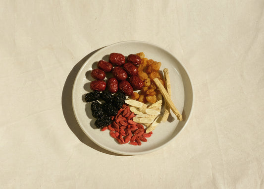 Chinese herbal tea blend on a plate with red dates jujube, black dates, goji berries, astragalus bei qi, codonopsis dang shen, longan. Image 1